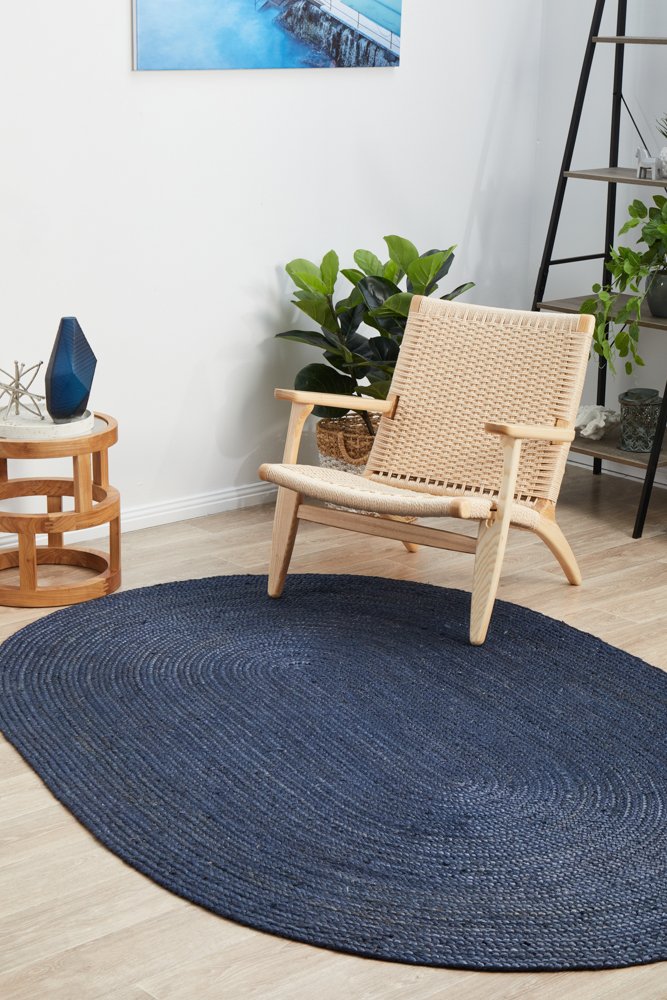 Round blue rug on a wooden floor with a wicker chair and plants in the background.