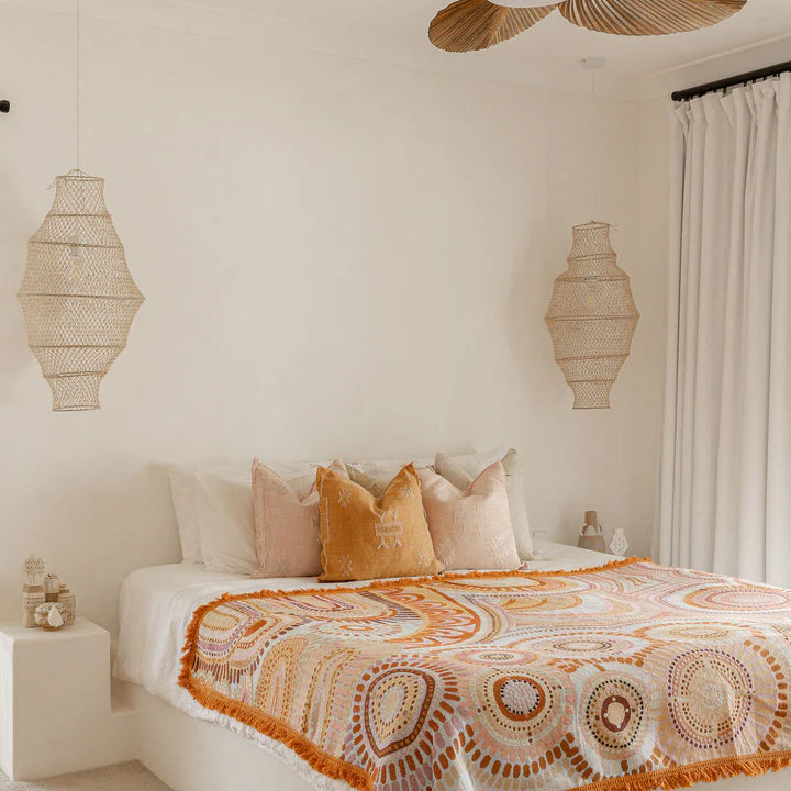 Bedroom with a ceiling fan, lamps, and a patterned bedspread.