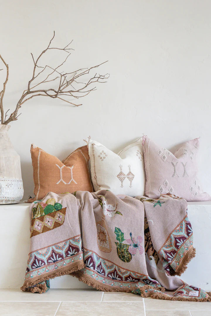 Decorative pillows and blanket with cactus design on a white surface