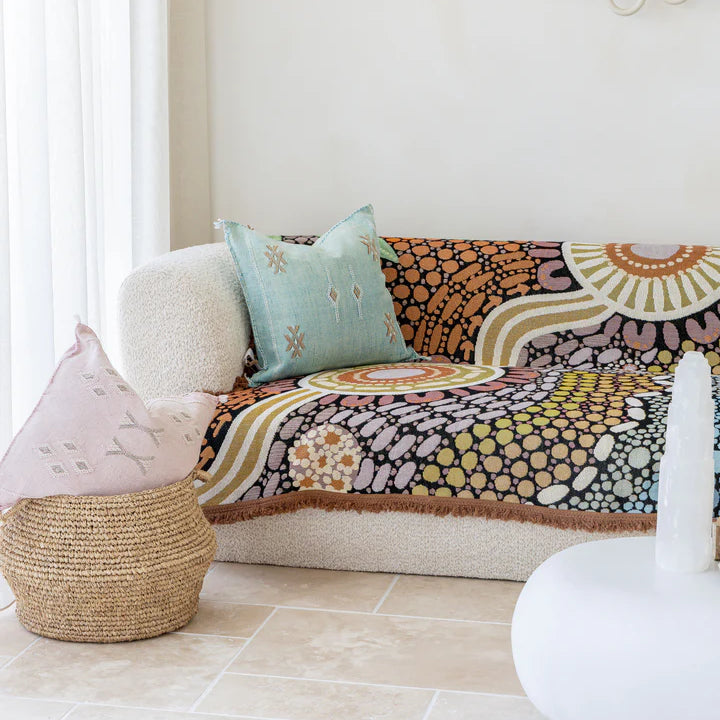 Decorative sofa with colorful patterned throw blanket and cushions in a living room setting.