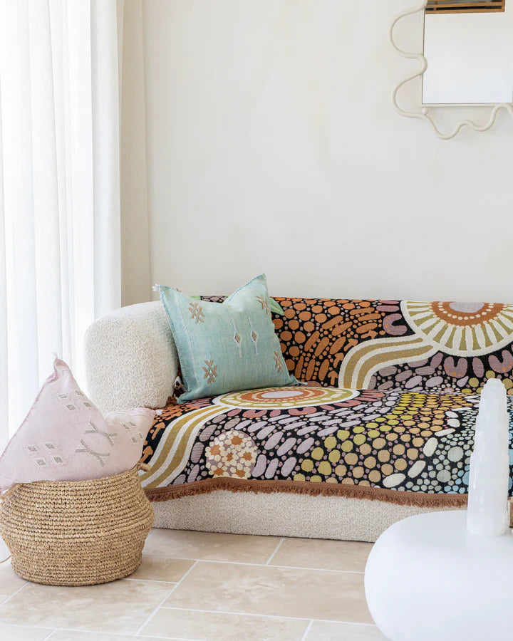 Decorative sofa with colorful patterned throw blanket and cushions in a living room setting.