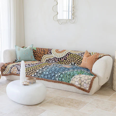 Decorative quilt on a sofa in a bright living room with a mirror and candles.