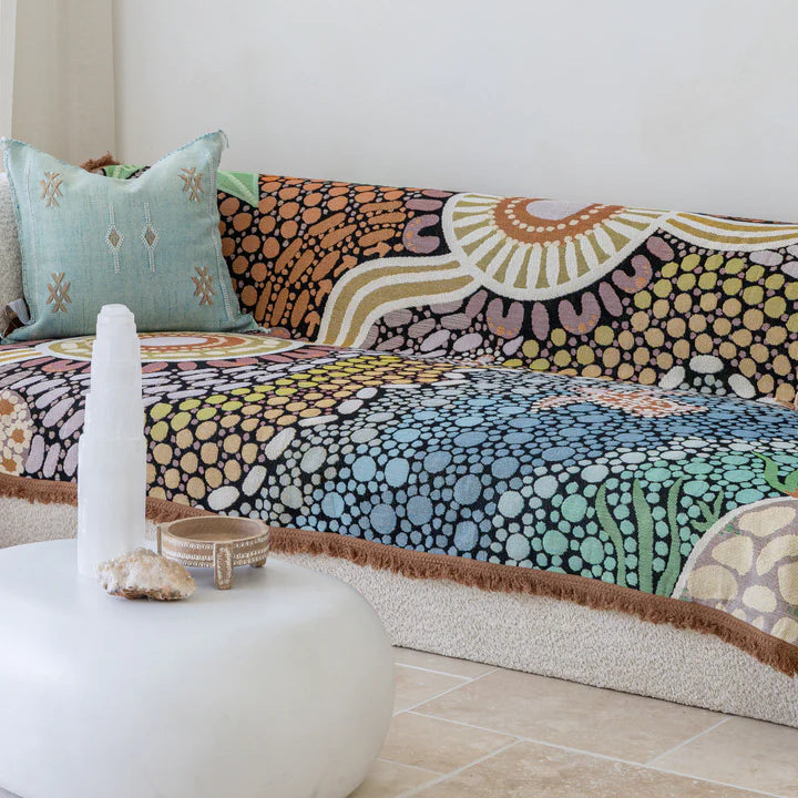 Colorful patterned sofa with a white ottoman and decorative items in a room.