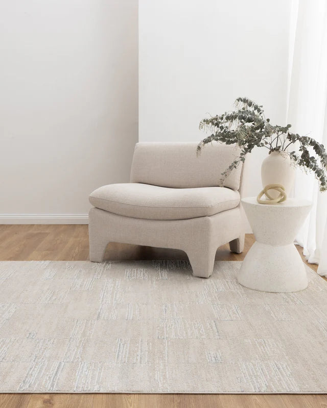 Beige armchair and side table with a plant in a minimalistic room.