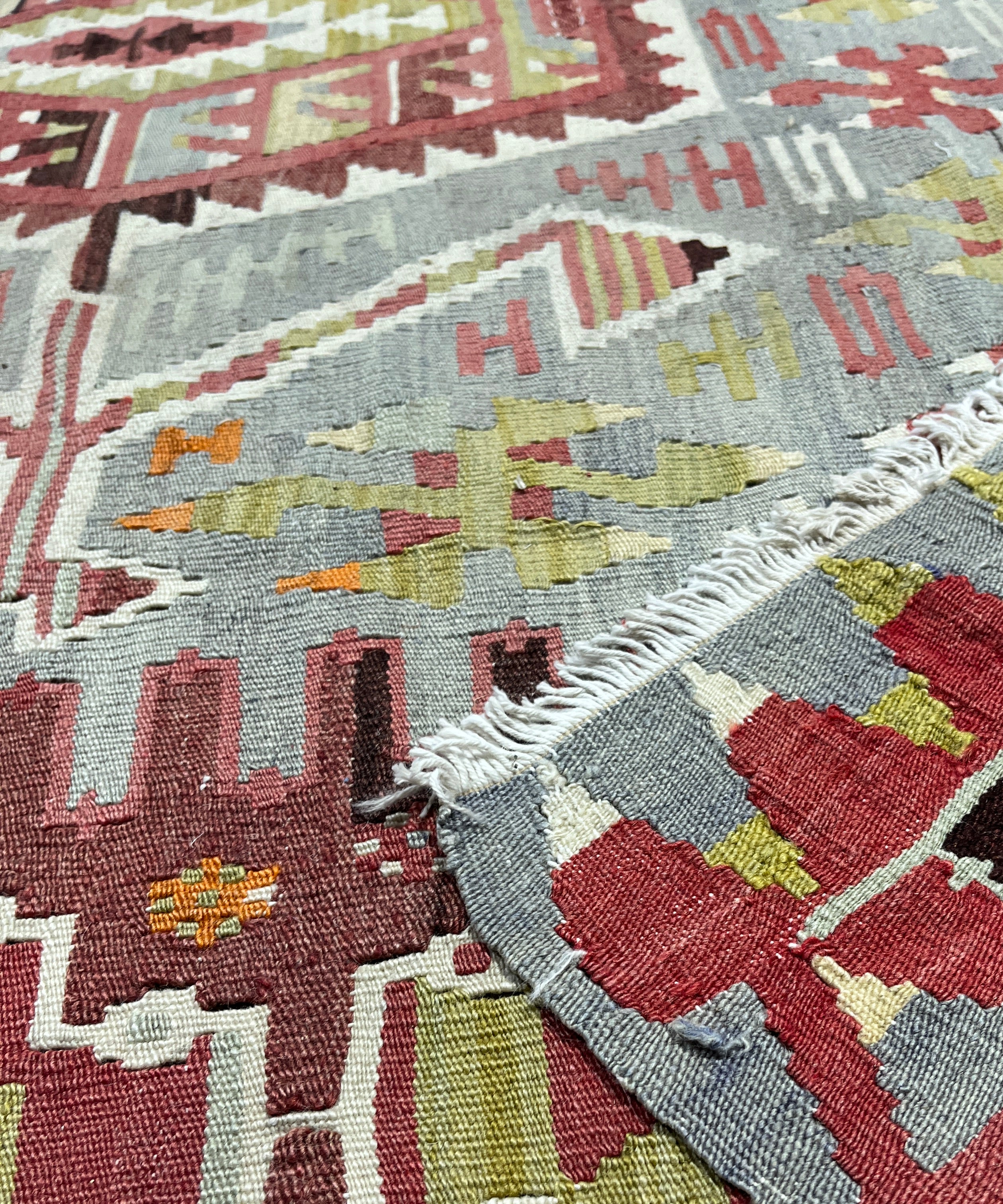 Close-up of patterned rugs with geometric designs in red, gray, and green.