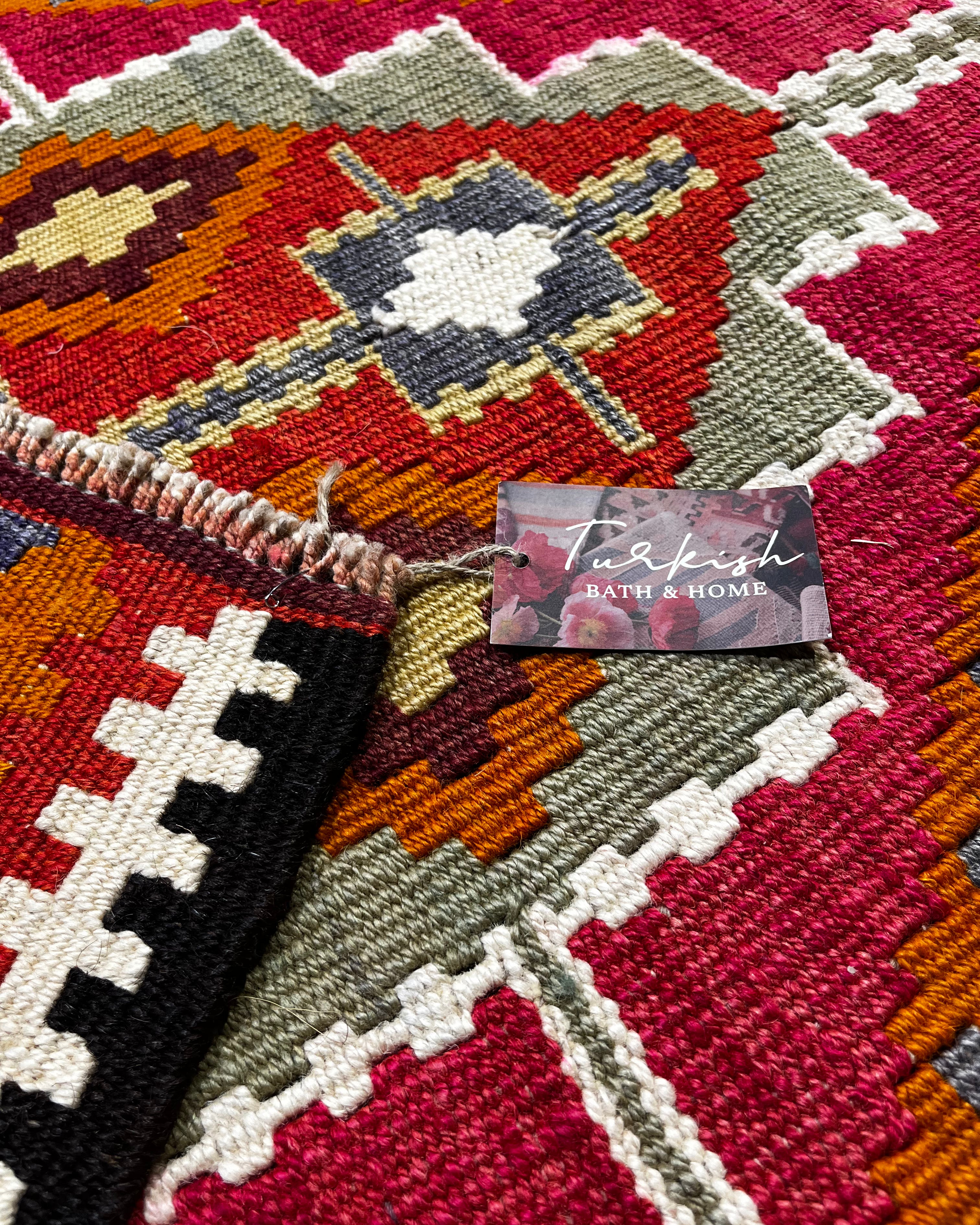 Close-up of a Turkish bath and home product label on a patterned rug.