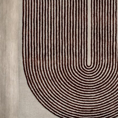 A close-up of a textured area rug featuring a modern U-shaped design with concentric arches in dark brown and beige on a light beige base.