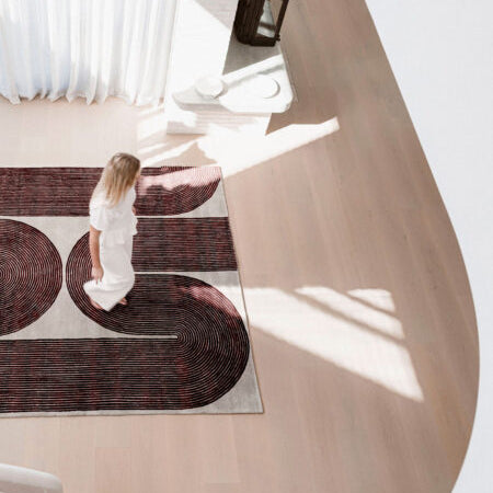 Woman walking on a patterned rug in a modern interior setting