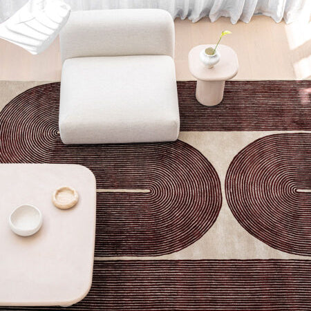 Modern living room with a patterned rug, white armchair, and side table.