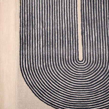 Close-up of a modern area rug with a U-shaped design featuring concentric arches in black on a beige background, shown on a light wood floor.