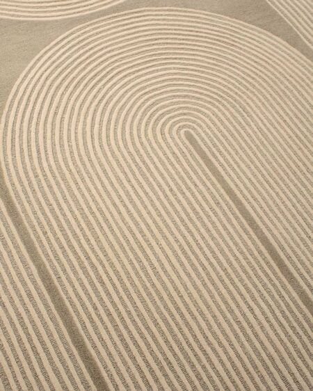 A close-up of a textured area rug featuring a modern, minimalist concentric arch pattern in warm beige and cream tones.
