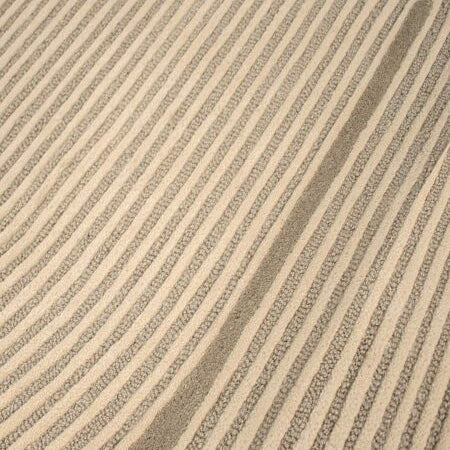 Close-up of a textured area rug with diagonal stripes in beige and taupe gray.