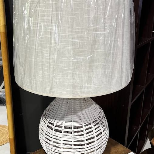 White woven lamp with a textured shade on a wooden surface.