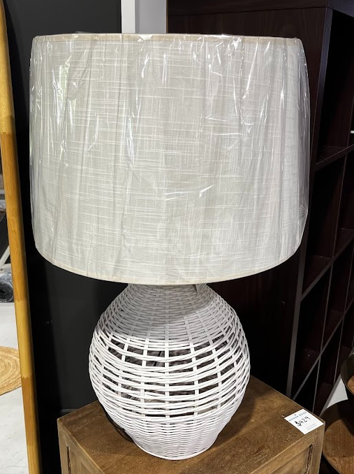 White woven lamp with a textured shade on a wooden surface.