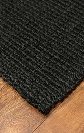 Close-up of a black textured rug on wooden flooring