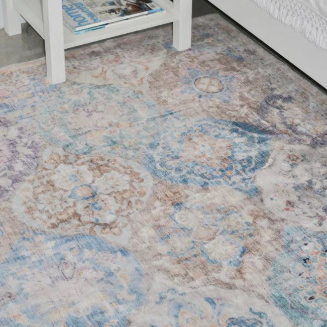 Patterned rug on a floor with a white table and books in the background