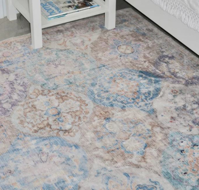 Patterned rug on a floor with a white table and books in the background