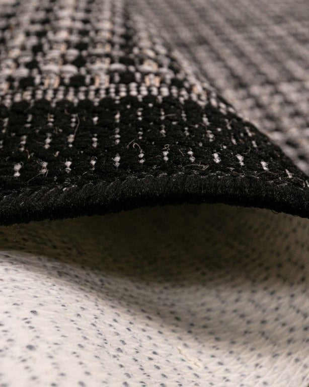 Close-up of textured black and gray rug with geometric pattern