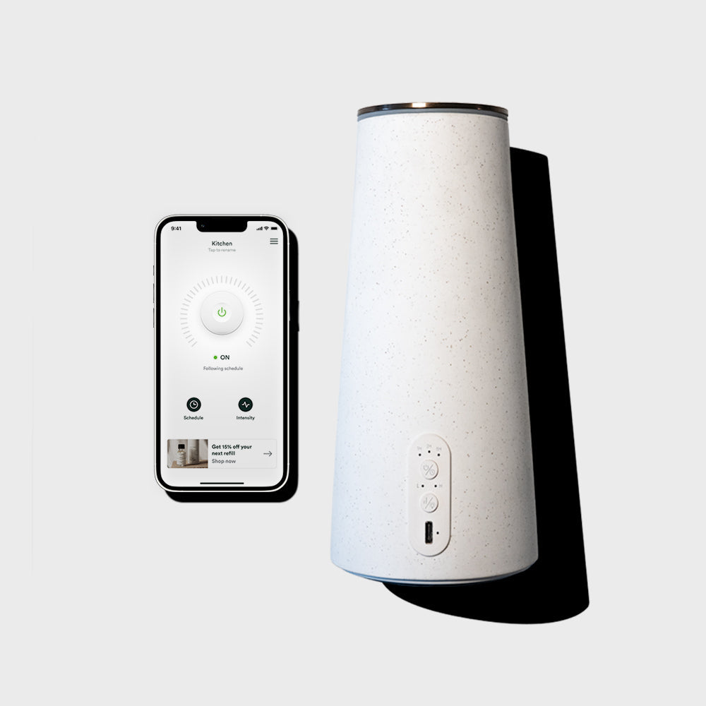 White humidifier with smartphone displaying humidifier app on a light gray background