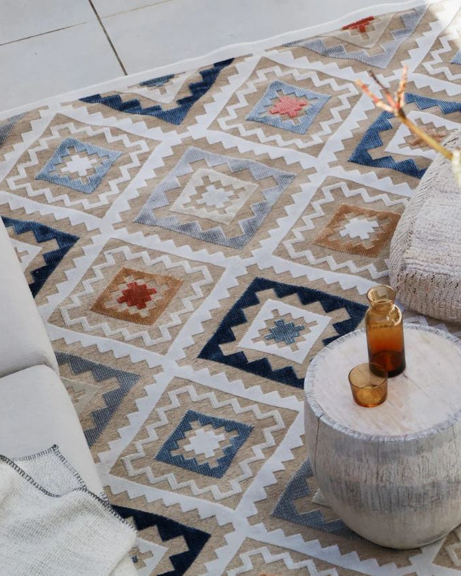 Patterned rug with a small table and candle on a light-colored floor