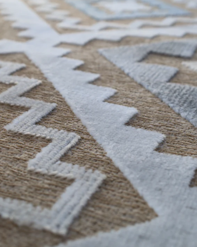 Close-up of a patterned rug with geometric designs in neutral colors.