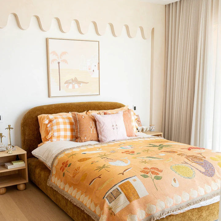 Bedroom with a bed covered in a colorful blanket and pillows, near a window with curtains.