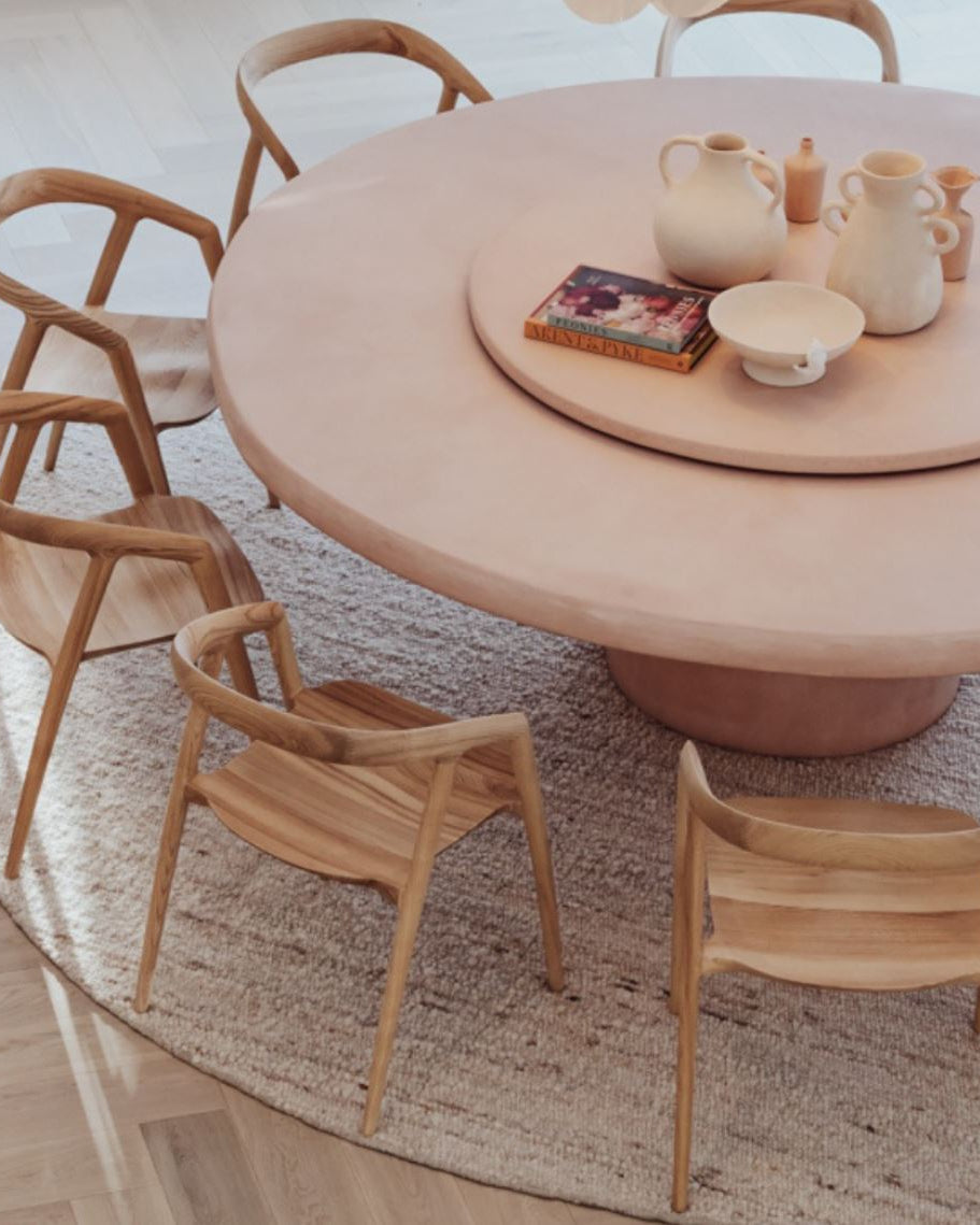 Round wooden dining table with chairs in a room setting