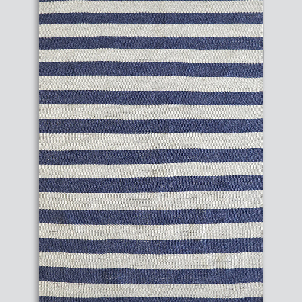 A rectangular woven rug with horizontal navy blue and off-white stripes, finished with natural jute fringe on the top and bottom edges, shown flat against a light gray background.