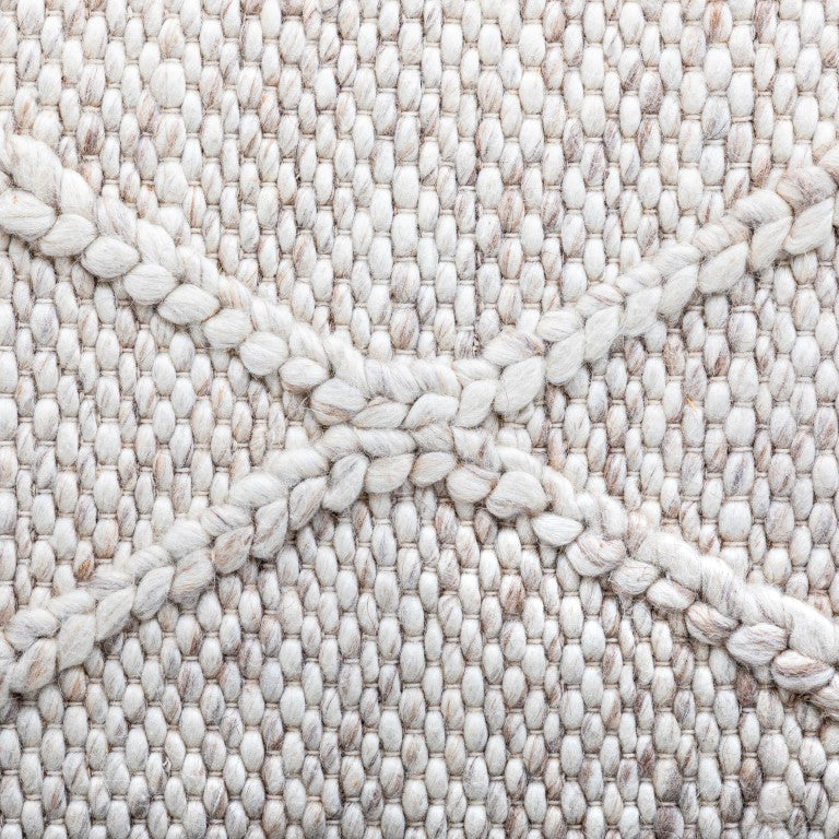 Close-up view of the Colombo beige rug highlighting the detailed braided diamond pattern and the rich, soft texture of the hand-woven New Zealand wool.