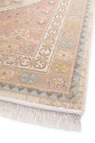 Close-up of a patterned rug with decorative border and fringe on a white background