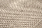 Close-up of a textured beige fabric with a woven pattern