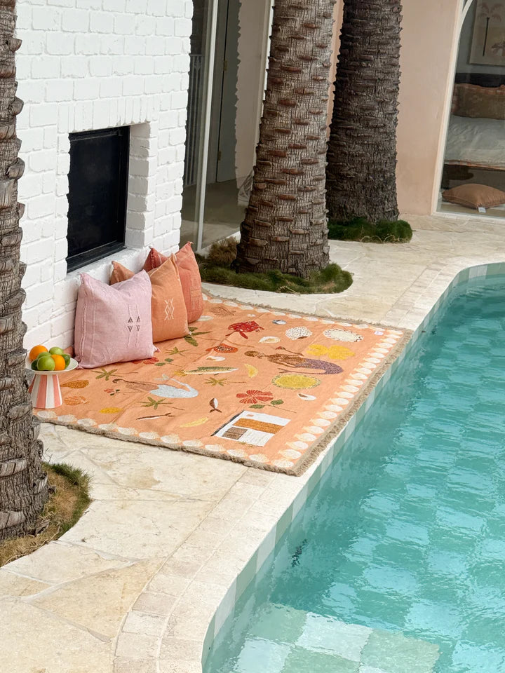 Outdoor seating area with colorful rug by a poolside