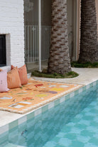 Colorful towel on a poolside with palm trees and a building in the background
