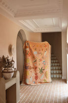 Decorative blanket with colorful patterns draped over a chair in a room with a tiled floor and decorative wall.