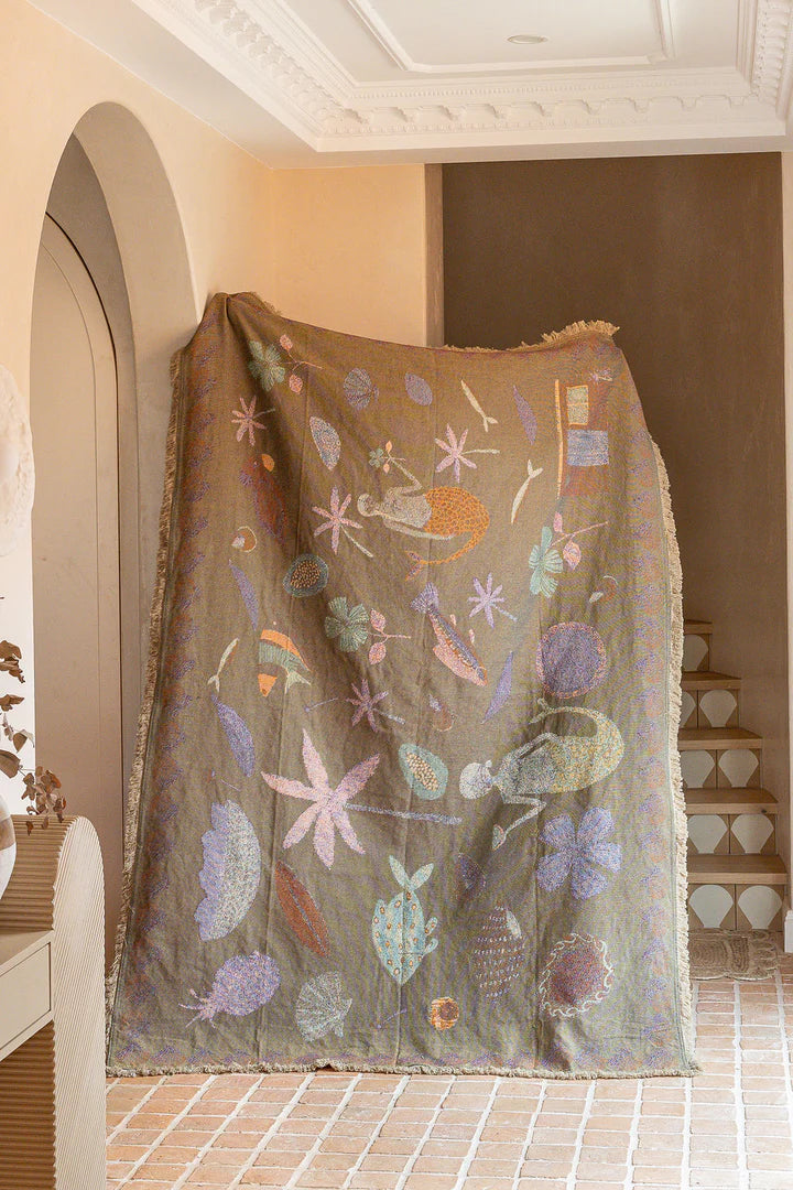 Decorative blanket with floral patterns draped over a chair in a room.