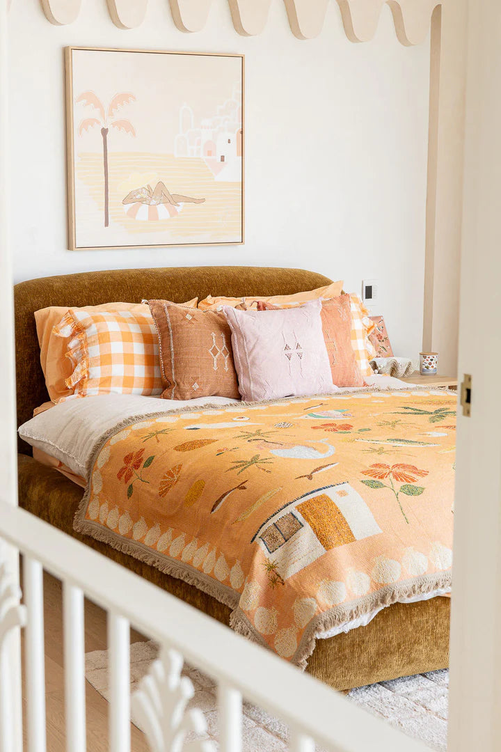 Bed with floral bedding and checkered pillows in a bedroom setting.
