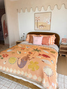 Bedroom with a bed featuring a colorful quilt and pillows, decorated with a wall art piece.