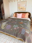 Bedroom with a colorful quilt featuring mermaid designs, pillows, and a painting on the wall.