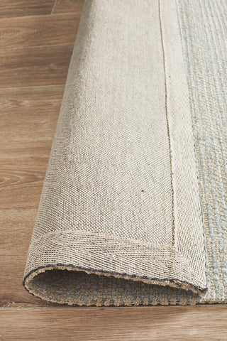 Image of the Allure Rug in Sky colour rolled up, revealing both the top and the underside, showcasing the consistent quality and finish of the rug's hand-loomed craftsmanship.