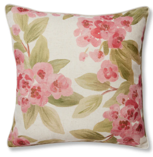 A square decorative throw pillow featuring a watercolor-style floral print of pink blossoms and green leaves on a cream linen-textured background.