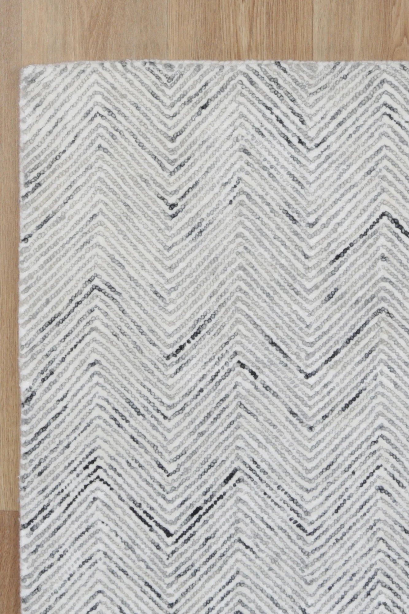 Detailed close-up of the Astrid Grey Rug's herringbone texture, emphasizing the luxurious blend of wool and viscose.