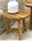 Wooden stool with a white ceramic vase on a light wooden floor.