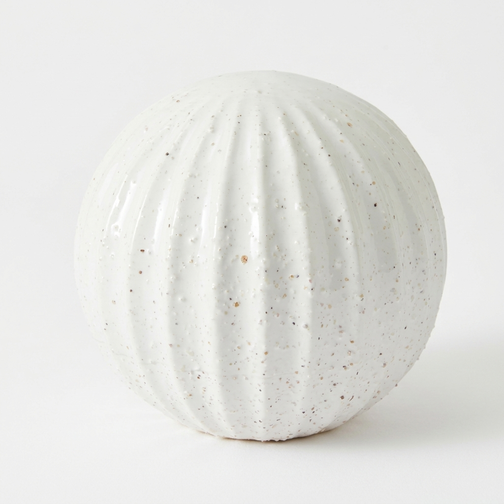 A round, ribbed ceramic vase in a speckled off-white glaze, photographed against a seamless white background.