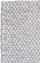 Close-up of a textured woven rug with a geometric pattern.
