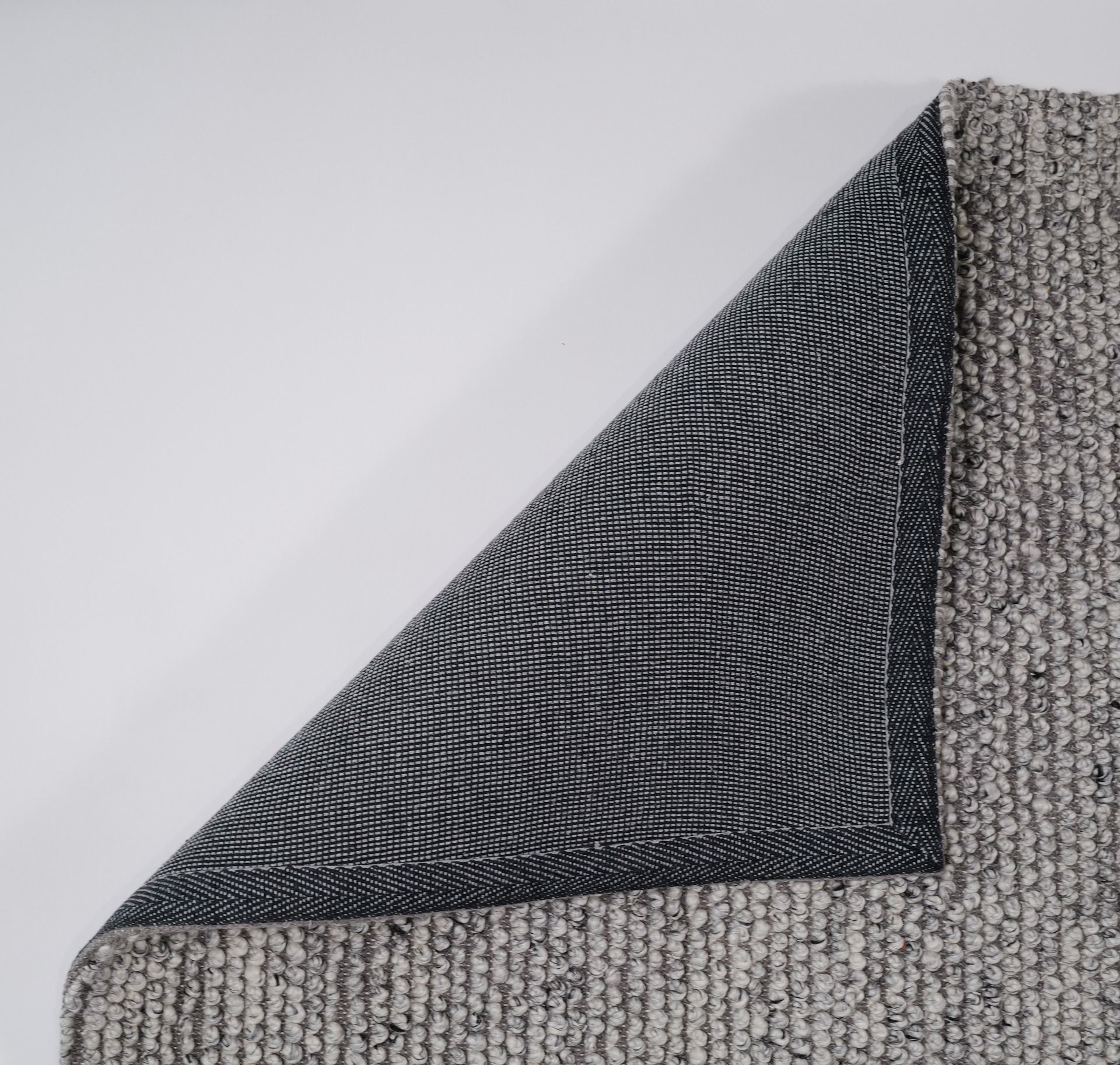 Gray textured rug corner on a white background