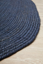 Close-up of a dark blue braided rug on a wooden floor