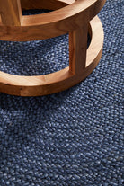Wooden cat tree with a blue sisal-wrapped platform on a blue carpet.