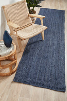 Woven blue rug on a wooden floor with a wicker chair and side table.