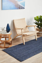Nautical-themed room with a woven chair, side table, and blue rug.