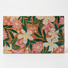 A rectangular woven doormat featuring a vibrant floral pattern with pink and cream flowers, green leaves, and yellow centers on a warm brown background, shown against a plain white studio backdrop.